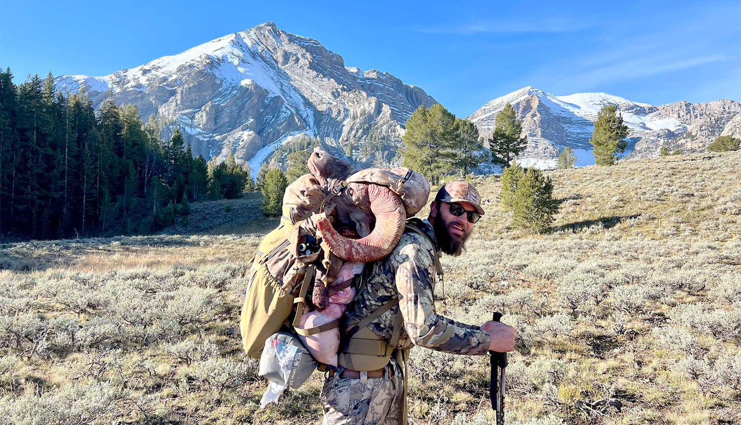 Male hunter in mountains packing out meat and sheep skull