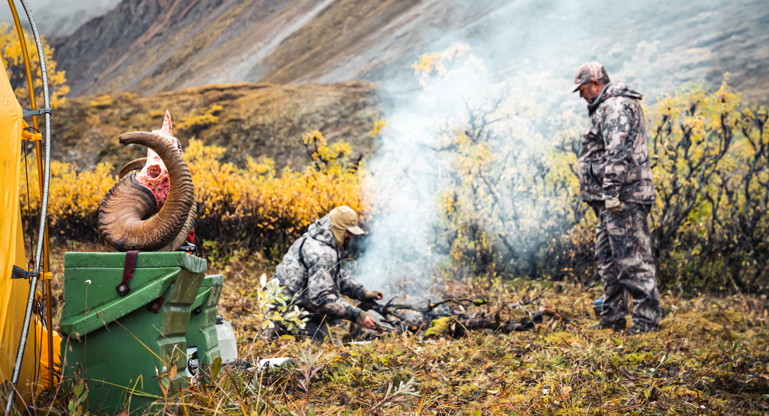 Hunters starting a fire at camp after a successful hunt