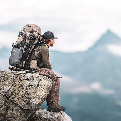 Hunter with loaded pack looking over a valley