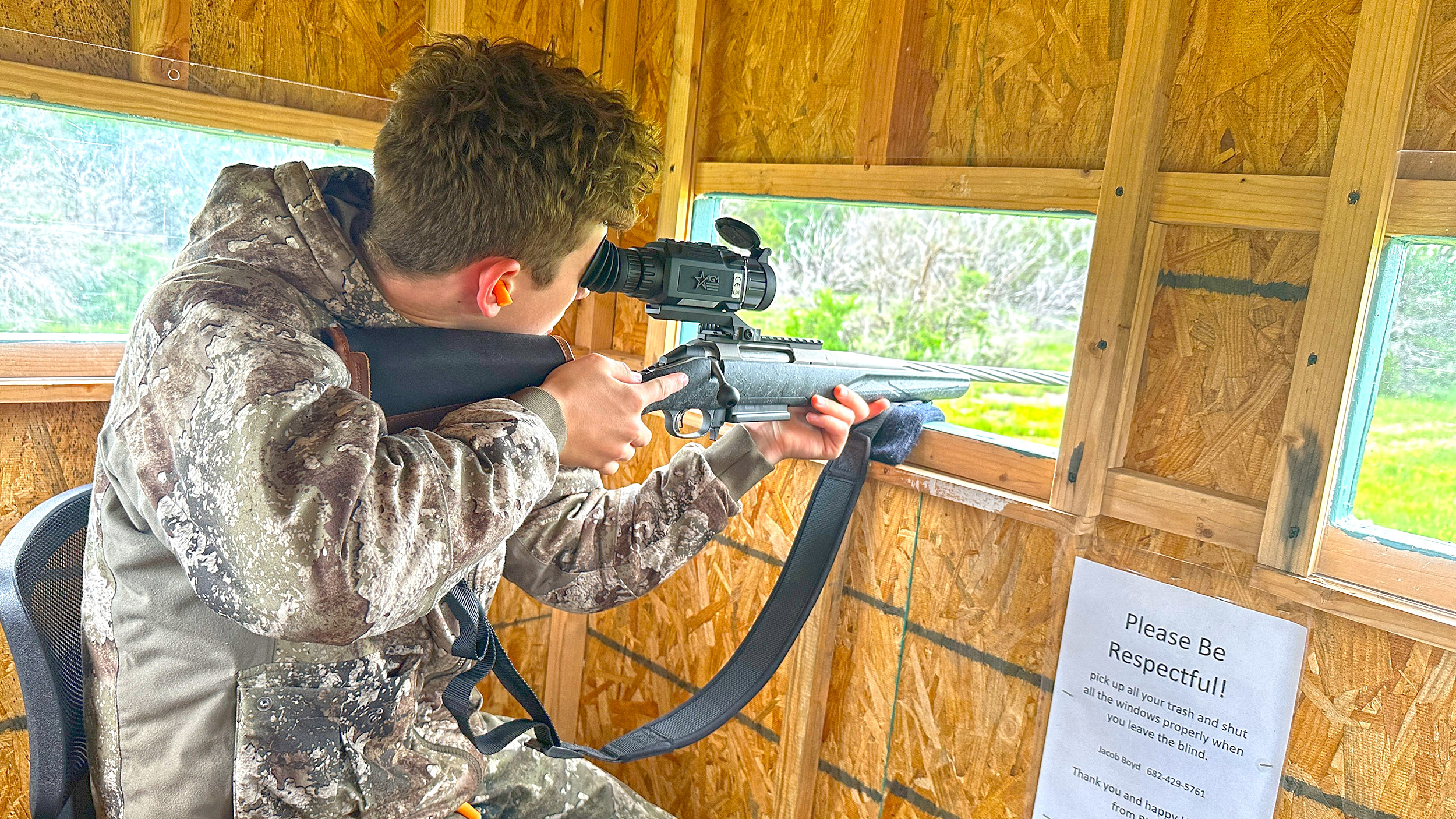 Youth hunter shooting a rifle from a blind