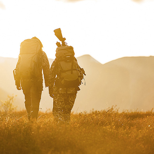 Hunters walking through a field in the golden light